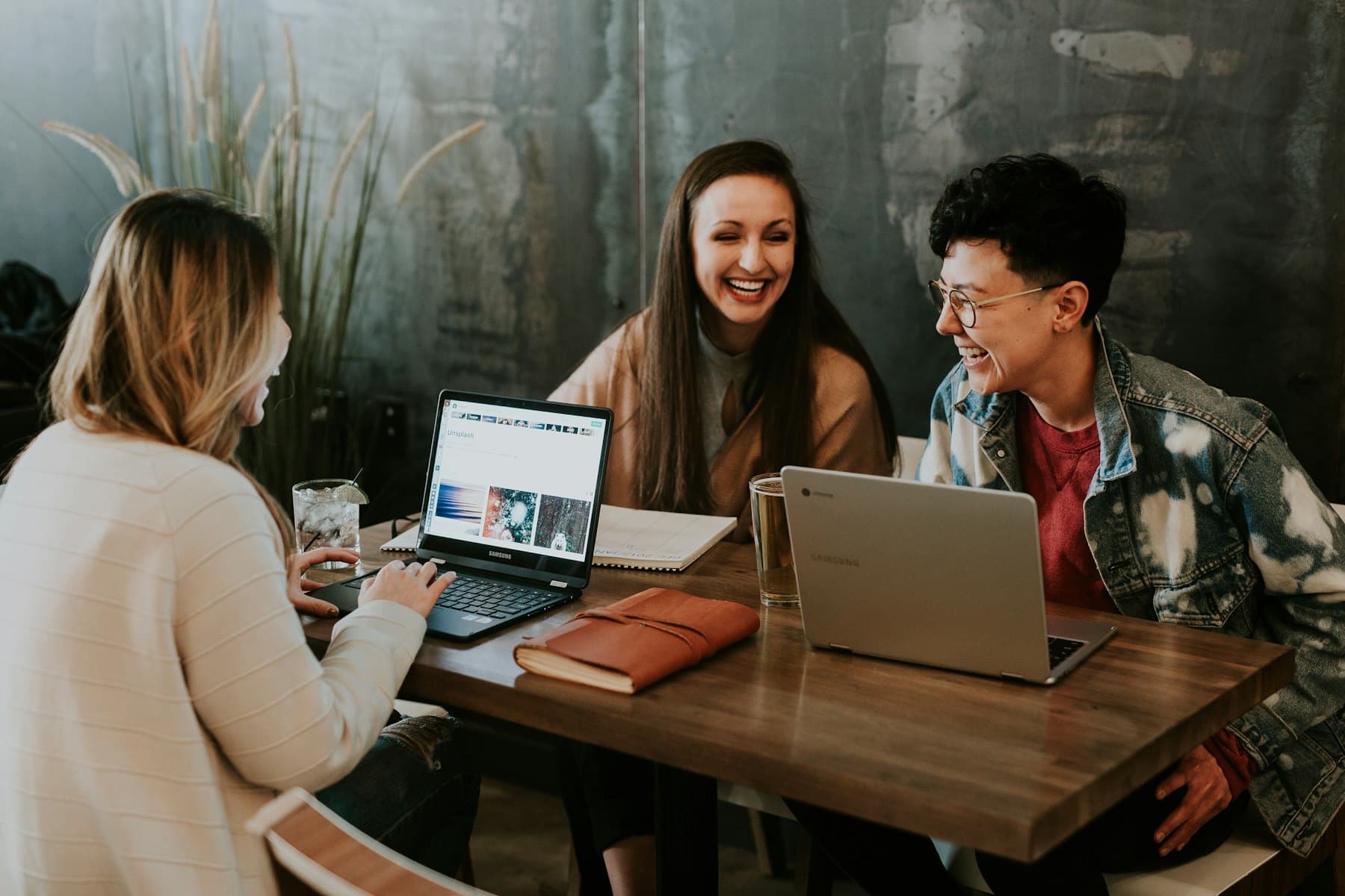 Three people talking around a table with laptops